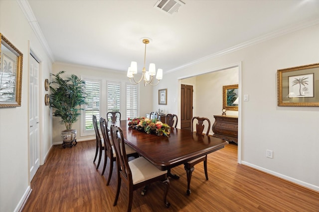 dining room featuring dark wood-style floors, visible vents, a notable chandelier, and crown molding