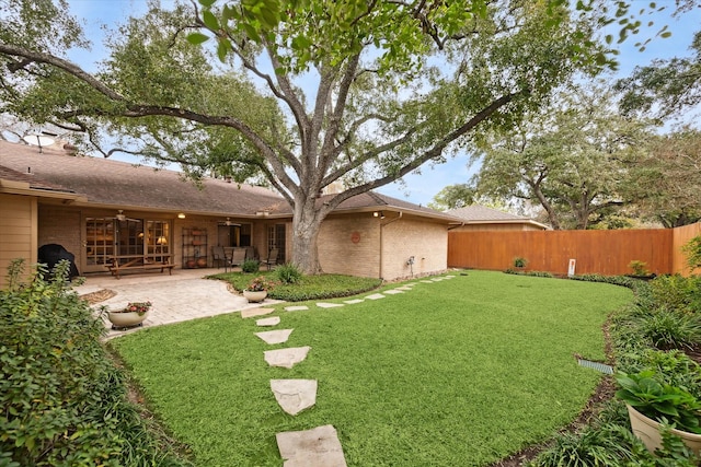 view of yard featuring fence, a ceiling fan, and a patio