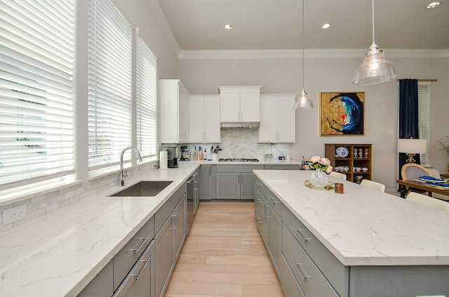 kitchen with ornamental molding, gray cabinets, a sink, and a center island