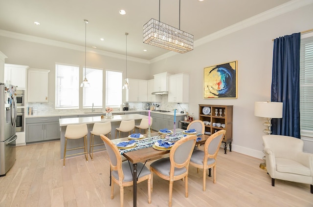 dining space featuring light wood-style floors, baseboards, and ornamental molding