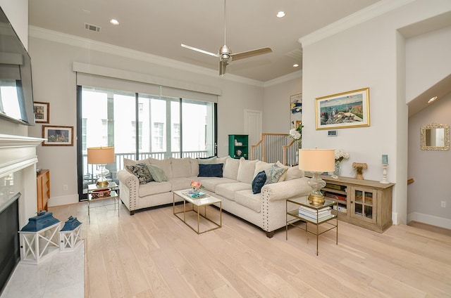 living room featuring light wood finished floors, ornamental molding, a fireplace, and visible vents