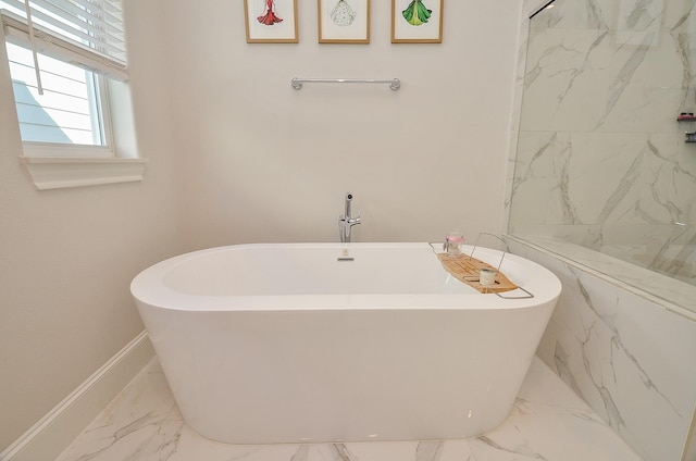 full bathroom with marble finish floor, a freestanding bath, and baseboards