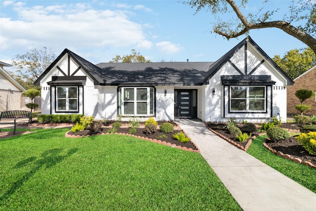 english style home featuring brick siding, a front lawn, and roof with shingles