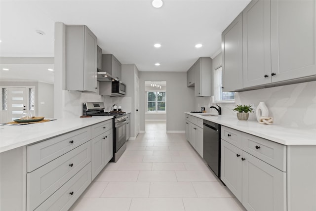 kitchen with appliances with stainless steel finishes, light countertops, a sink, and gray cabinetry