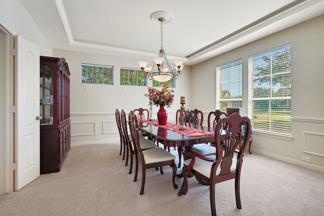 dining space with light carpet, a chandelier, a raised ceiling, and a decorative wall