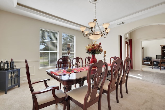 dining space with arched walkways, a tray ceiling, decorative columns, light colored carpet, and visible vents