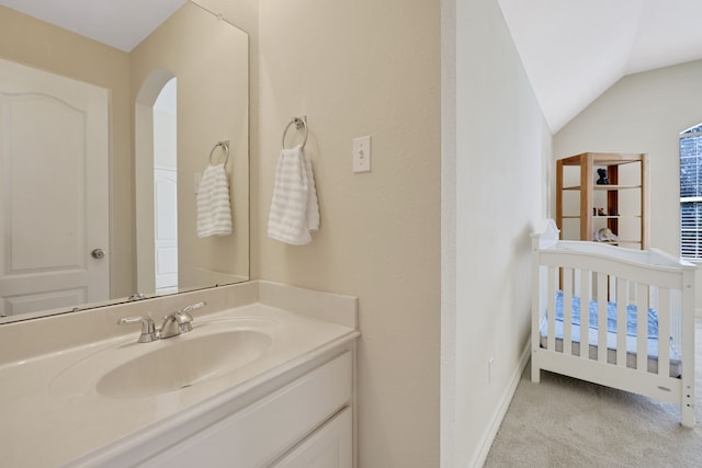 bathroom featuring baseboards, vaulted ceiling, and vanity