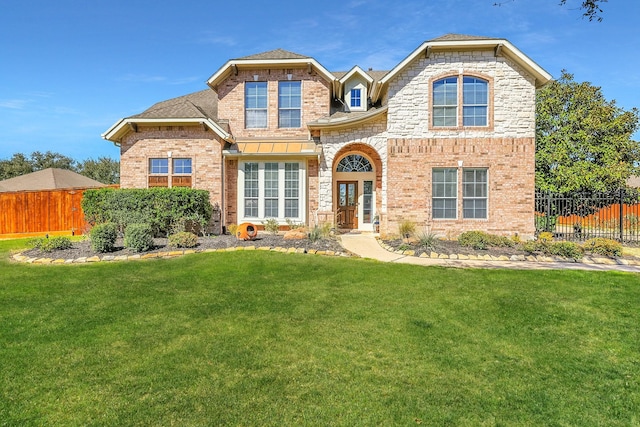 view of front of home featuring fence, a front lawn, and brick siding