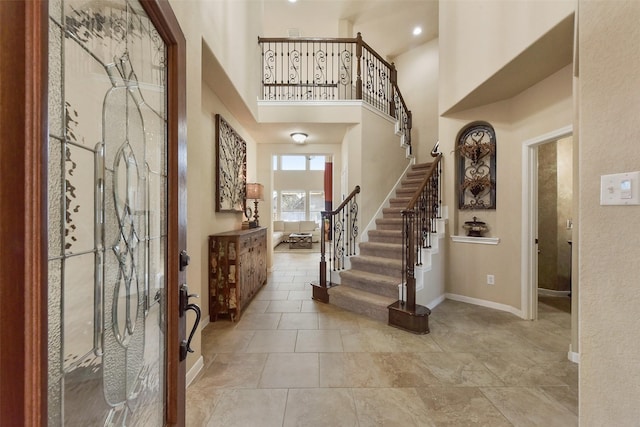 entrance foyer featuring a towering ceiling, stairs, and baseboards