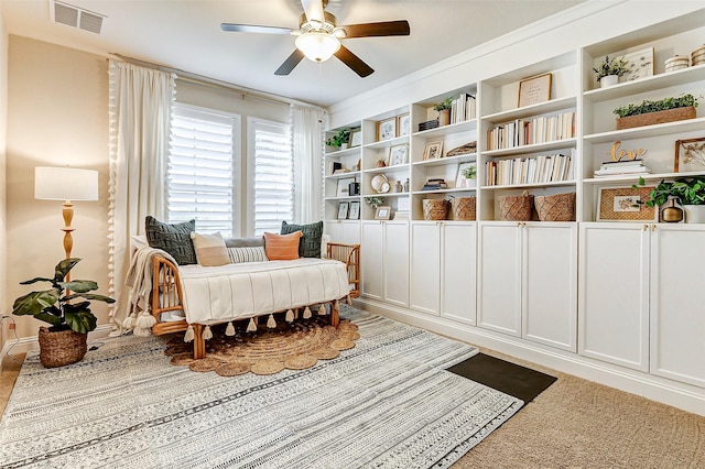 living area featuring built in features, visible vents, and a ceiling fan