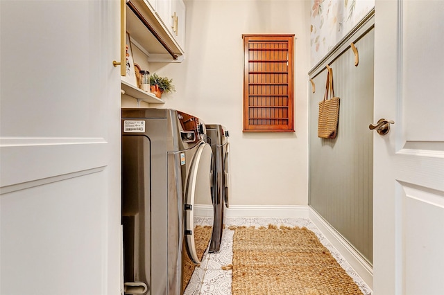 laundry room featuring baseboards, cabinet space, washing machine and clothes dryer, and tile patterned floors