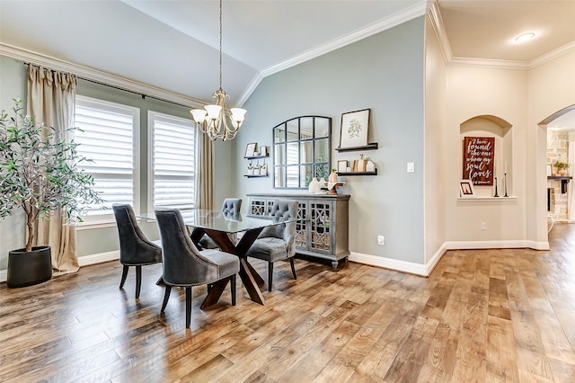 dining area featuring lofted ceiling, an inviting chandelier, ornamental molding, and wood finished floors