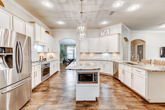 kitchen featuring arched walkways, stainless steel appliances, visible vents, a sink, and a chandelier