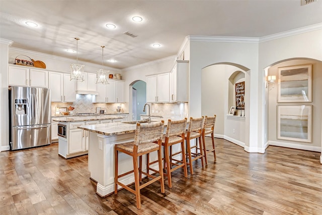 kitchen featuring light stone counters, a breakfast bar area, a sink, white cabinetry, and appliances with stainless steel finishes