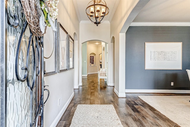 entryway featuring arched walkways, baseboards, wood finished floors, and crown molding