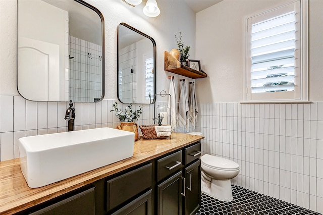 bathroom with toilet, tile patterned flooring, tile walls, and vanity