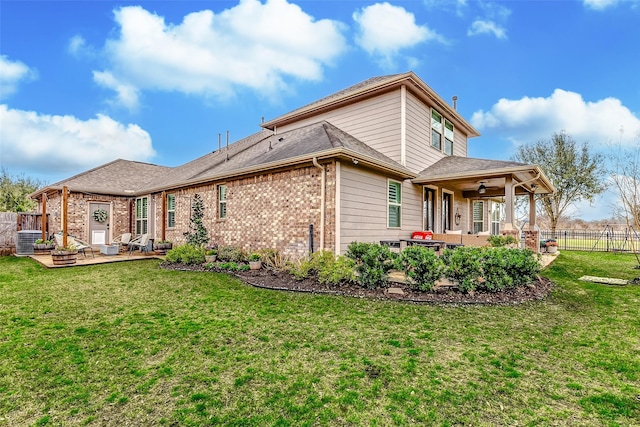 rear view of house featuring a yard, a patio area, brick siding, and fence