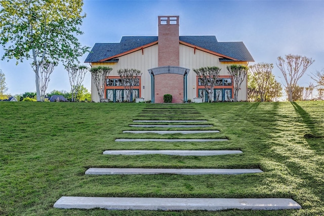 exterior space with a chimney and a lawn