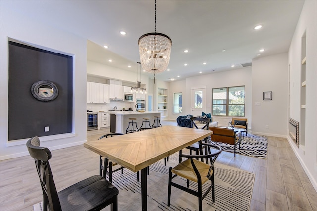 dining room with light wood finished floors, beverage cooler, visible vents, a notable chandelier, and recessed lighting