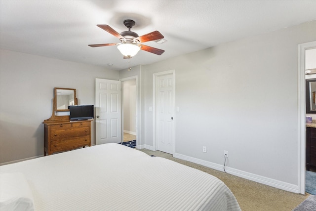 bedroom featuring a ceiling fan, light colored carpet, connected bathroom, and baseboards