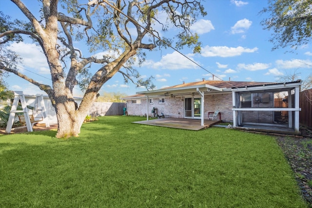 rear view of house featuring a yard, brick siding, and a fenced backyard