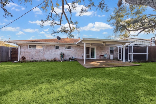 back of property with a ceiling fan, a fenced backyard, a lawn, and brick siding