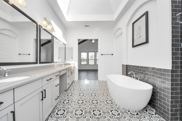 bathroom with a freestanding tub, a sink, tile walls, and double vanity