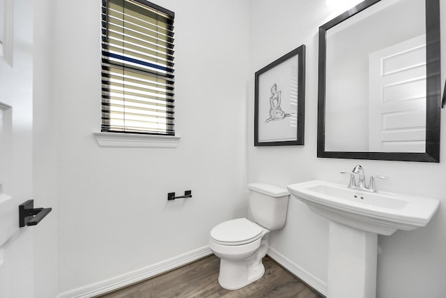 bathroom with toilet, a sink, baseboards, and wood finished floors