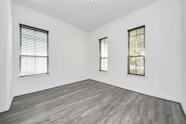 spare room with baseboards and wood finished floors