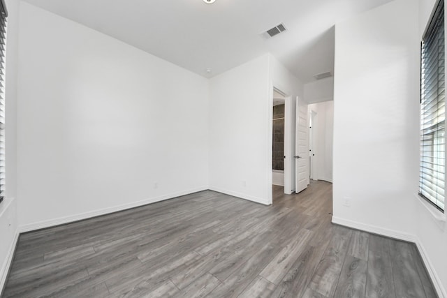 spare room with baseboards, visible vents, and wood finished floors