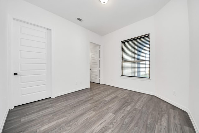 spare room with visible vents, baseboards, and wood finished floors