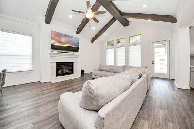 living room with lofted ceiling with beams, baseboards, wood finished floors, and a glass covered fireplace