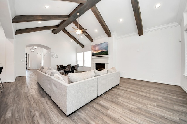 living area featuring vaulted ceiling with beams, a fireplace, arched walkways, and wood finished floors