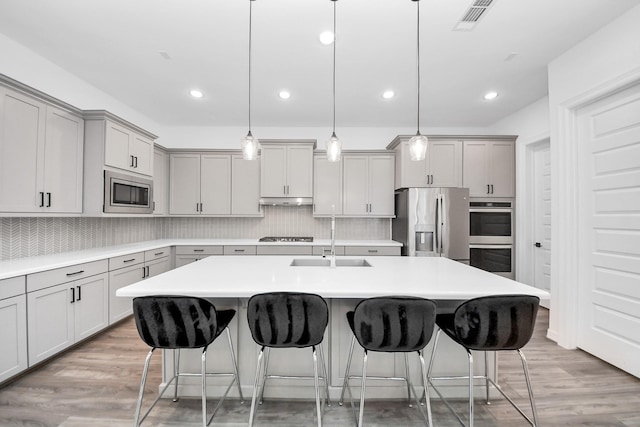 kitchen with stainless steel appliances, a sink, visible vents, and gray cabinetry