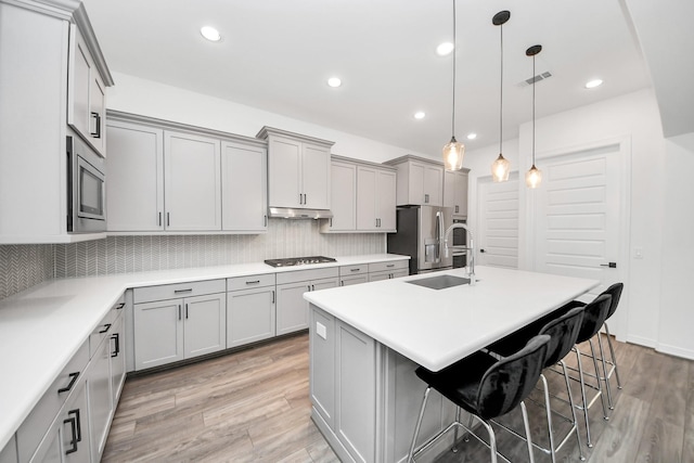 kitchen with tasteful backsplash, visible vents, appliances with stainless steel finishes, gray cabinets, and under cabinet range hood