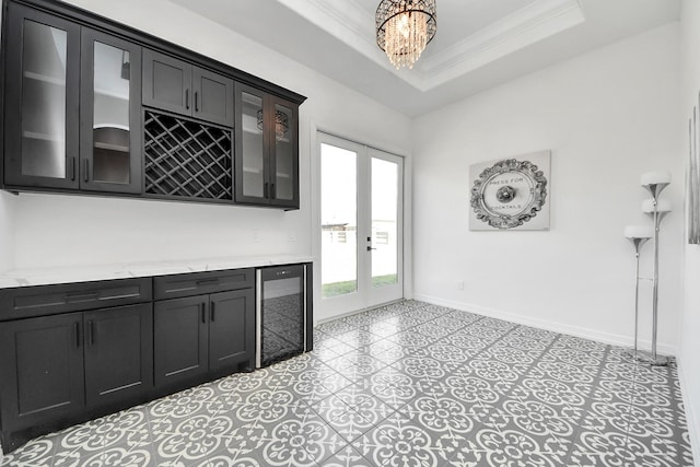 interior space featuring a dry bar, baseboards, a raised ceiling, wine cooler, and crown molding