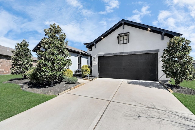 view of front facade with a front yard, concrete driveway, and stucco siding