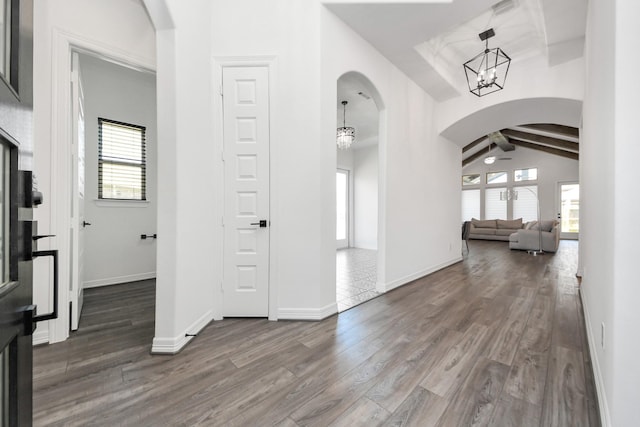 entryway featuring arched walkways, dark wood finished floors, a wealth of natural light, and a chandelier