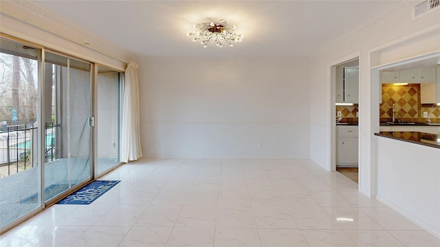 unfurnished room featuring ornamental molding, visible vents, a sink, and baseboards