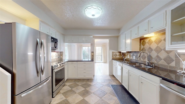 kitchen with appliances with stainless steel finishes, dark countertops, a sink, and decorative backsplash