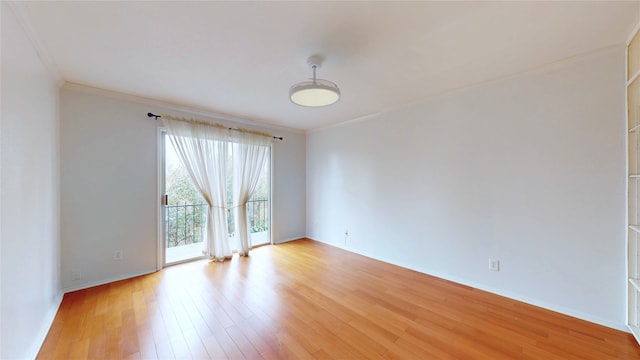 empty room featuring ornamental molding, light wood-type flooring, and baseboards