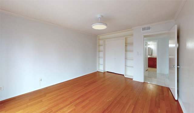 unfurnished bedroom with crown molding, a closet, visible vents, light wood-type flooring, and baseboards