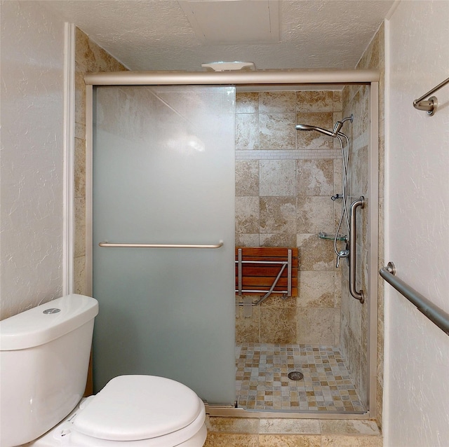 full bath featuring a textured ceiling, a textured wall, a shower stall, and toilet