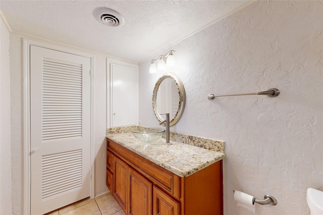 bathroom featuring visible vents, a textured wall, a textured ceiling, and vanity