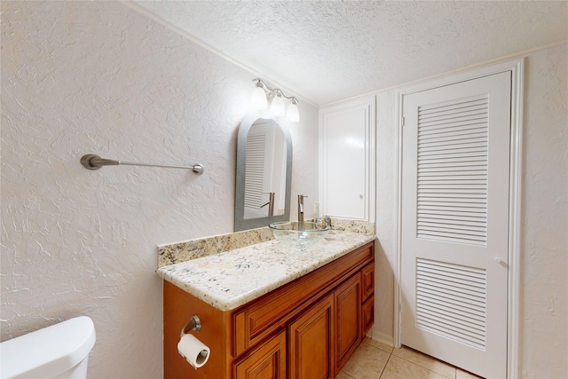 half bath with toilet, vanity, a textured ceiling, and a textured wall