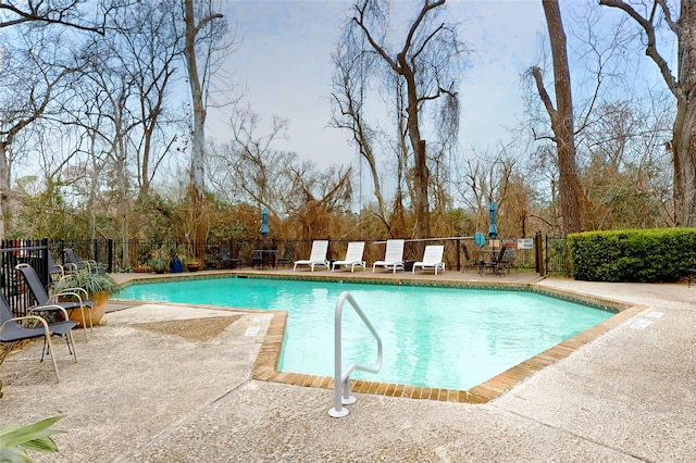 community pool with a patio area and a fenced backyard