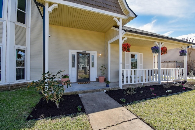 doorway to property featuring a porch and a lawn