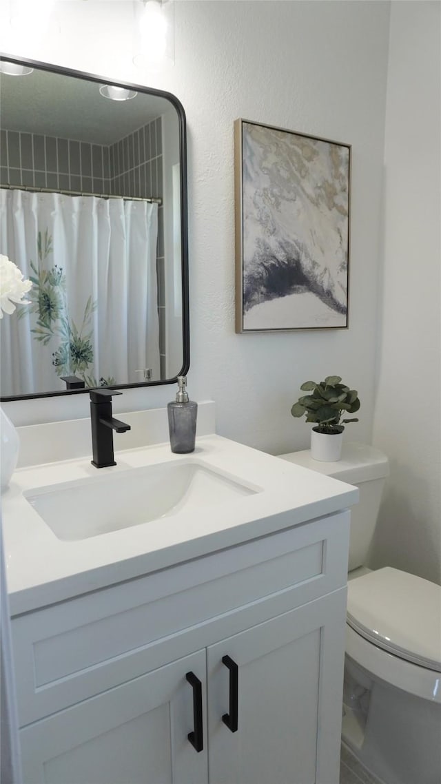 bathroom featuring toilet, vanity, and a shower with curtain