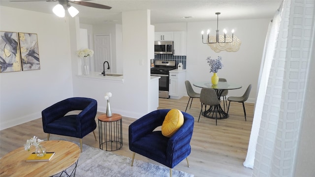 sitting room with light wood finished floors, baseboards, and a chandelier