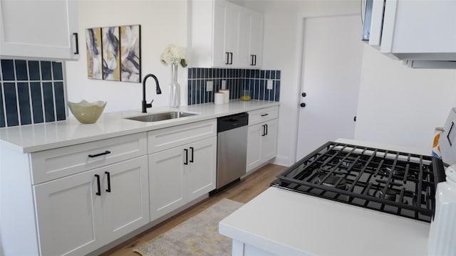 kitchen with light countertops, backsplash, white cabinets, a sink, and dishwasher